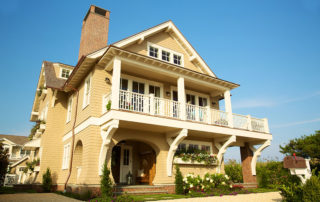 A large beige house with a balcony and porch.