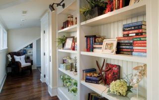 A white bookcase filled with books and plants.