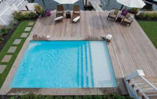 A pool with an umbrella and chairs on the deck