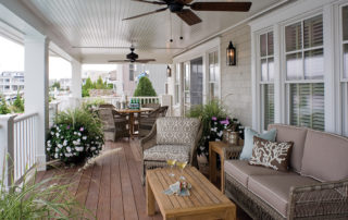 A porch with furniture and plants on the side.