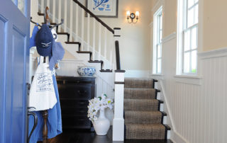 A blue door and white stairs in the hallway.