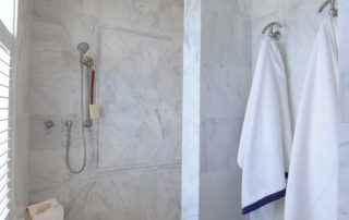 A bathroom with marble walls and white towels.