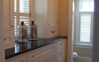 A bathroom with white cabinets and black counter tops.