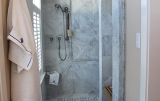 A walk in shower with marble walls and floor.