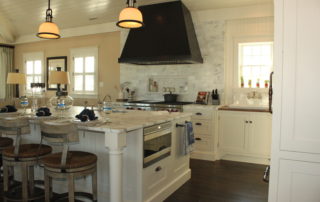 A kitchen with white cabinets and black hood