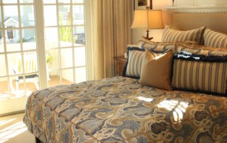 A bedroom with a bed, pillows and a lamp.