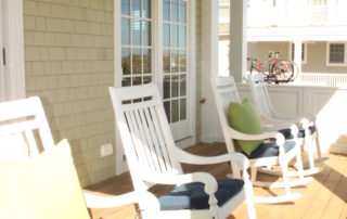 A porch with four rocking chairs and a door.