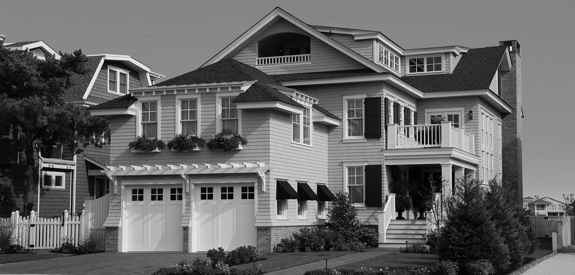 A black and white photo of a house with two garage doors.