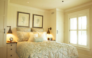 A bedroom with a bed, lamps and pictures on the wall.