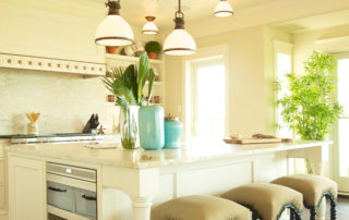 A kitchen with white cabinets and beige stools.