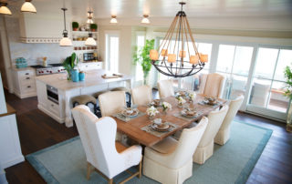 A dining room table with white chairs and a chandelier.