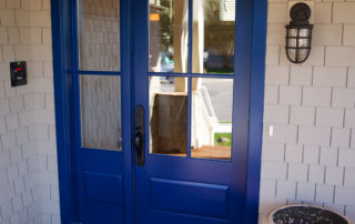 A blue door with two windows and a light on the outside.