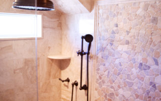 A shower with a tiled wall and a black fixture.