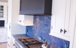 A kitchen with blue marble counter tops and white cabinets.