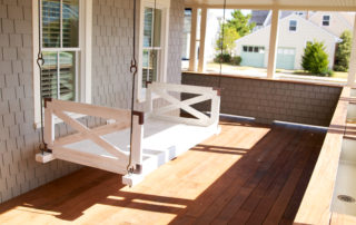 A porch swing with a white wooden frame.