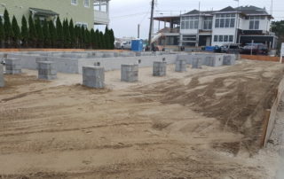 A beach front construction site with sand and concrete blocks.