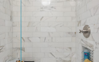 A bathroom with marble tile and glass shower door.