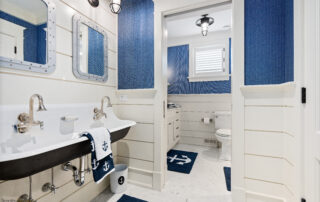 A bathroom with blue and white walls, a sink, toilet and mirror.