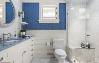 A bathroom with blue walls and white cabinets.