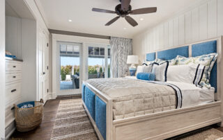 A bedroom with a bed, ceiling fan and sliding glass doors.