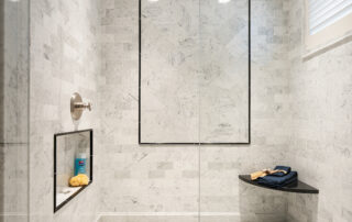 A bathroom with marble walls and floor, and a shower.