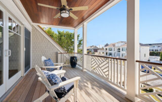 A porch with two chairs and a ceiling fan.