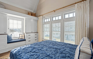 A bedroom with large windows and blue blanket.