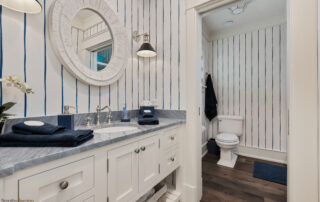 A bathroom with white cabinets and blue striped walls.