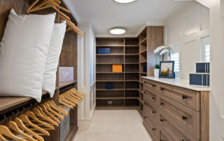 A walk in closet with many shelves and drawers.