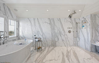 A bathroom with marble walls and floors, and a large tub.