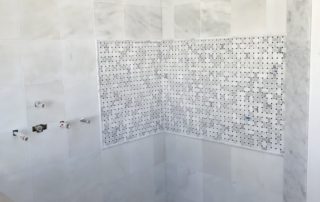 A bathroom with white tile and marble walls.