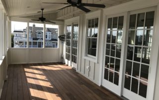 A porch with two windows and a ceiling fan.