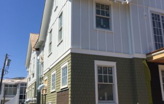 A row of houses with white trim and green siding.