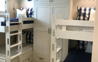 A room with bunk beds and white cabinets