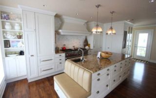 A kitchen with white cabinets and a bench in the middle of it.