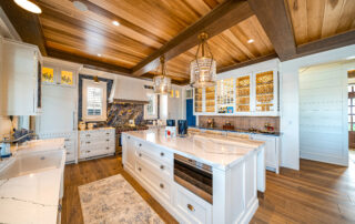 A kitchen with white cabinets and wooden ceiling.