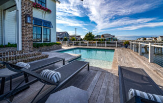 A pool with two lounge chairs and a deck.
